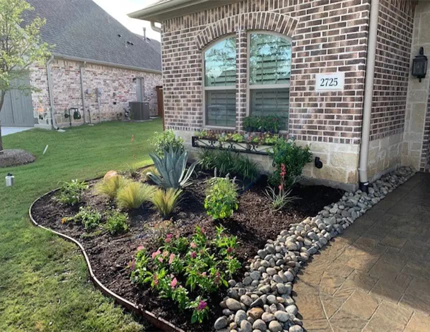 Finished Landmark landscape bed with river rock near the home