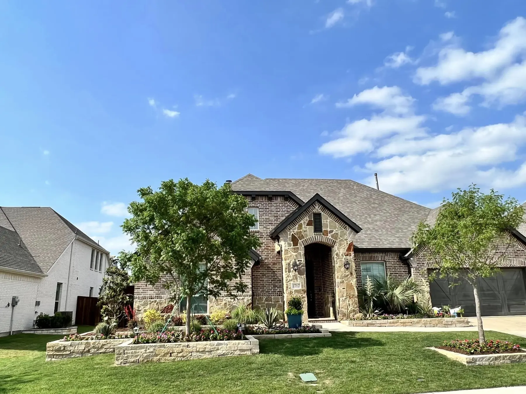 Completed residential front-yard landscaping project at a Prosper-area brick and stone home