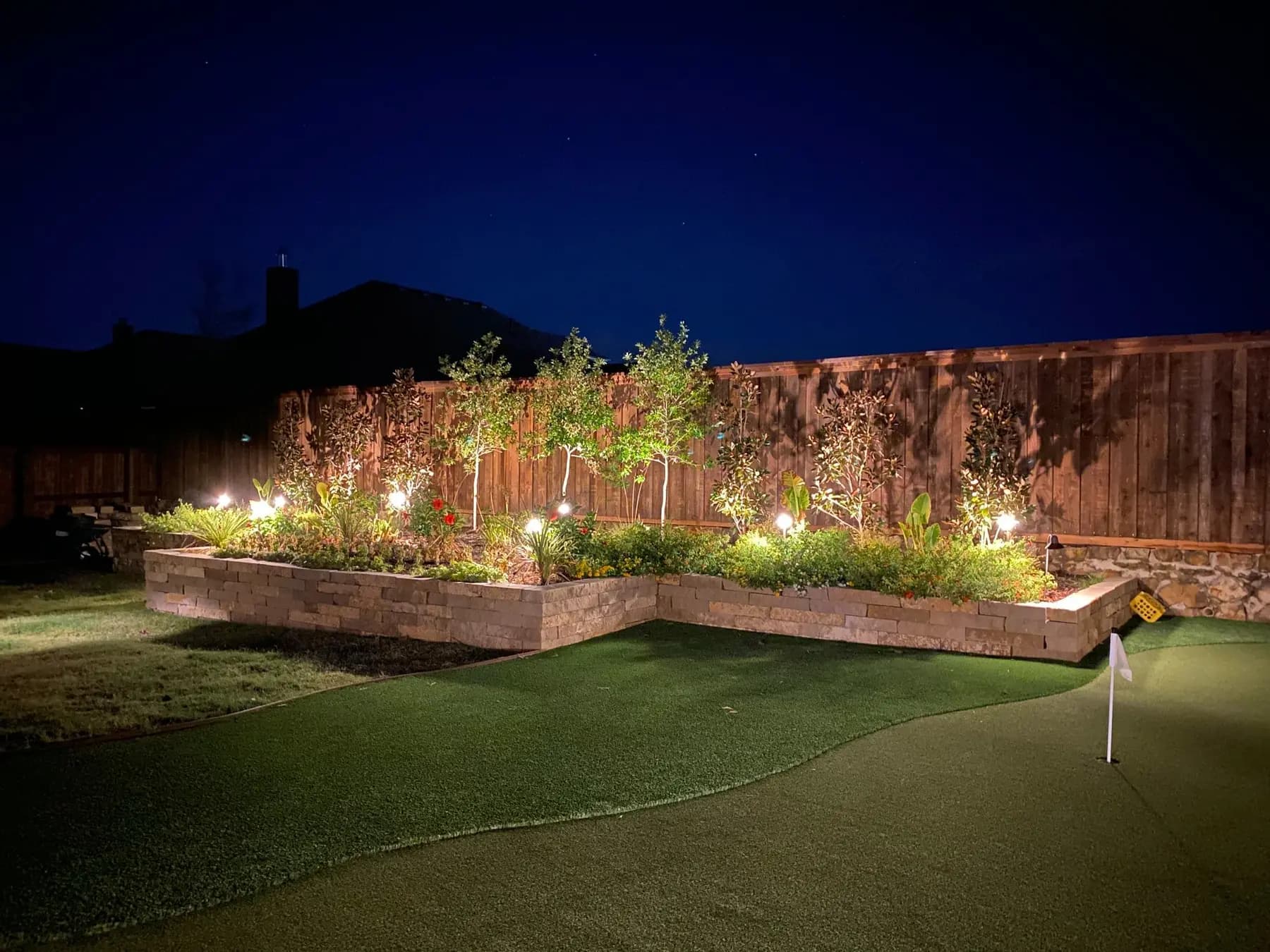 Warm landscape lighting highlighting a finished planting bed at a North Texas home