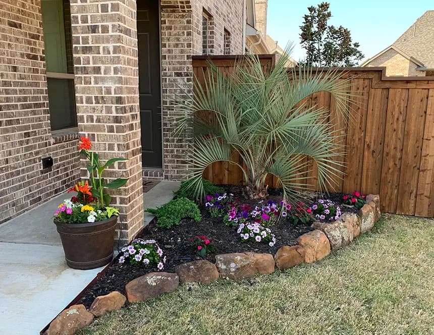 Landmark stone border and colorful planting beside a residential entry