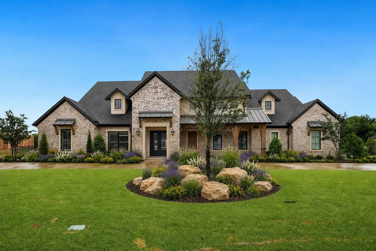 Upscale Texas home with a richly layered front landscape, ornamental grasses, flowers and natural stone